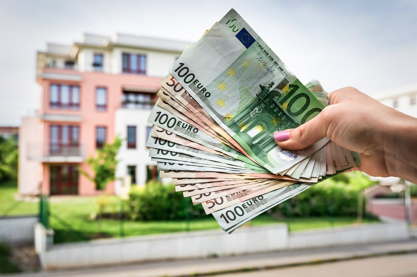 5.000 Euro Tippgeber-Prämie in bar vor einem Mehrfamilienhaus